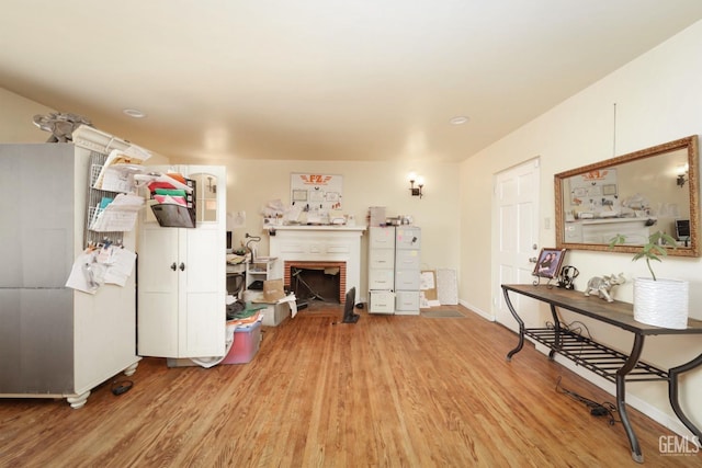 living room featuring light wood-type flooring and a brick fireplace