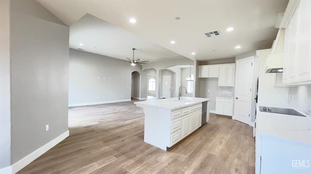 kitchen featuring white cabinetry, visible vents, arched walkways, and a sink