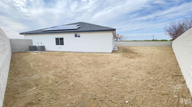 back of house with a fenced backyard, cooling unit, and solar panels