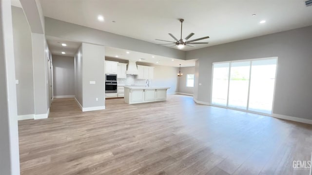 unfurnished living room featuring ceiling fan, recessed lighting, light wood-type flooring, and baseboards