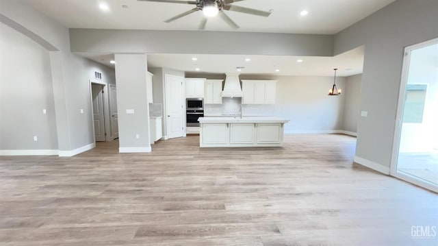 kitchen featuring light wood finished floors, recessed lighting, stainless steel microwave, visible vents, and open floor plan