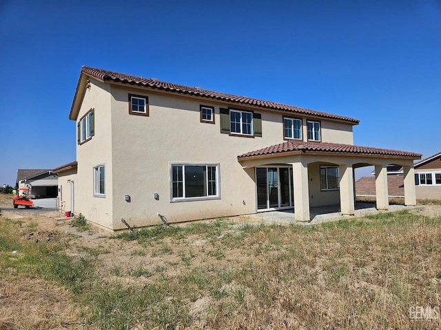 rear view of property featuring a tiled roof, a patio, and stucco siding