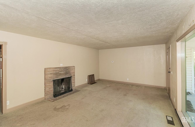 unfurnished living room with light colored carpet, a fireplace, a textured ceiling, baseboards, and visible vents