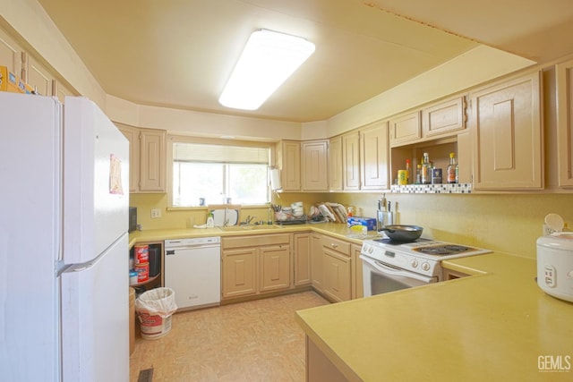 kitchen with light brown cabinets, white appliances, and sink