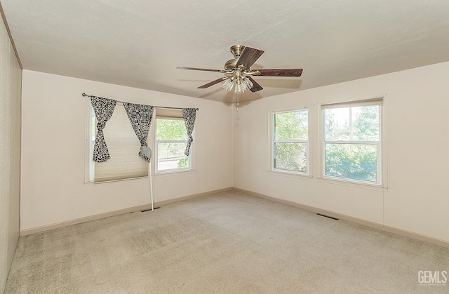 carpeted empty room featuring baseboards, a ceiling fan, and visible vents