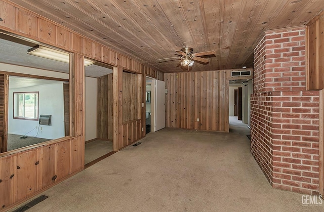 unfurnished living room with wooden walls, light carpet, a ceiling fan, wooden ceiling, and visible vents
