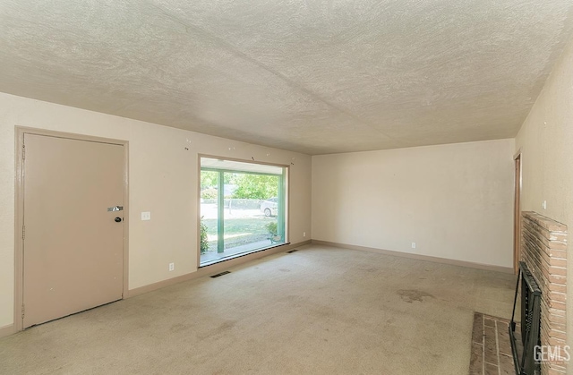 unfurnished living room featuring visible vents, a brick fireplace, baseboards, light colored carpet, and a textured ceiling