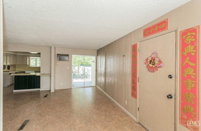 interior space featuring baseboards, a textured ceiling, a wall mounted AC, and visible vents