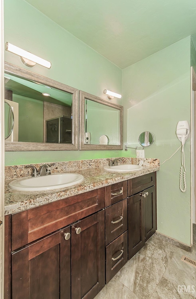 full bath featuring a sink, baseboards, double vanity, and visible vents