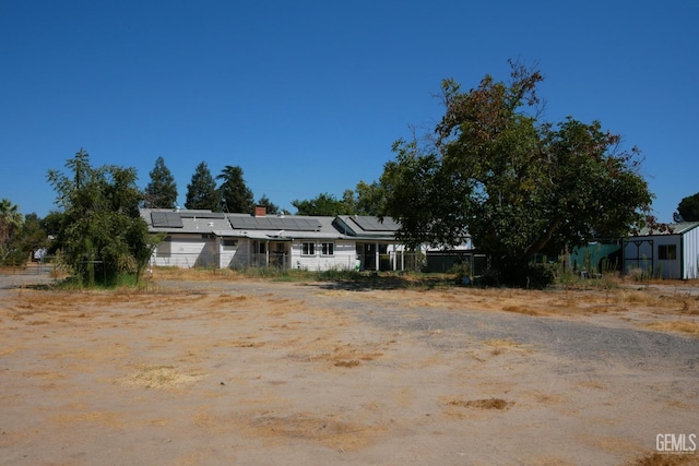 view of front facade with fence and roof mounted solar panels