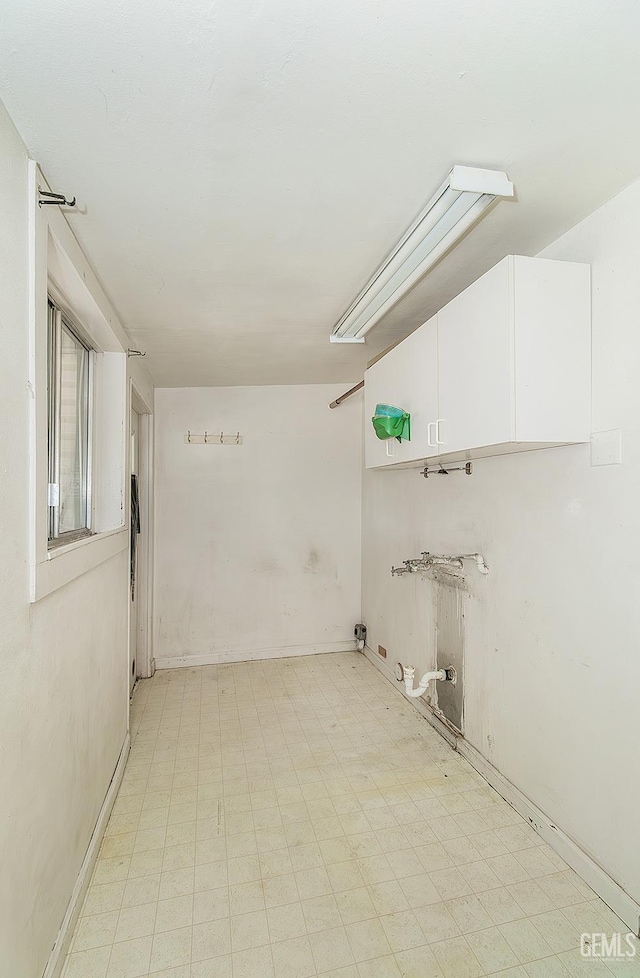 clothes washing area with laundry area, light floors, and baseboards