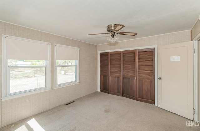 unfurnished bedroom with multiple windows, carpet, a closet, and visible vents