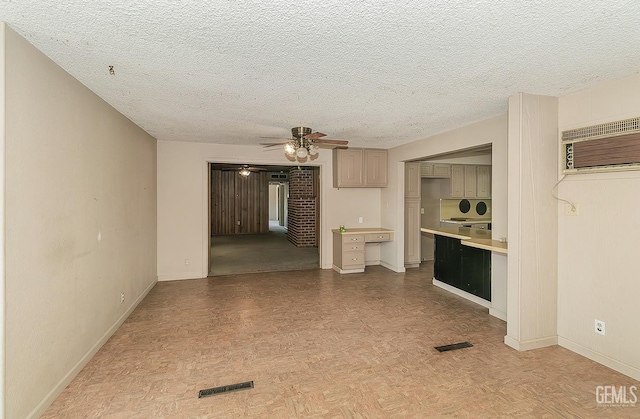 unfurnished living room with ceiling fan, visible vents, a textured ceiling, baseboards, and a wall mounted AC