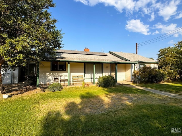 ranch-style home featuring solar panels, covered porch, and a front lawn