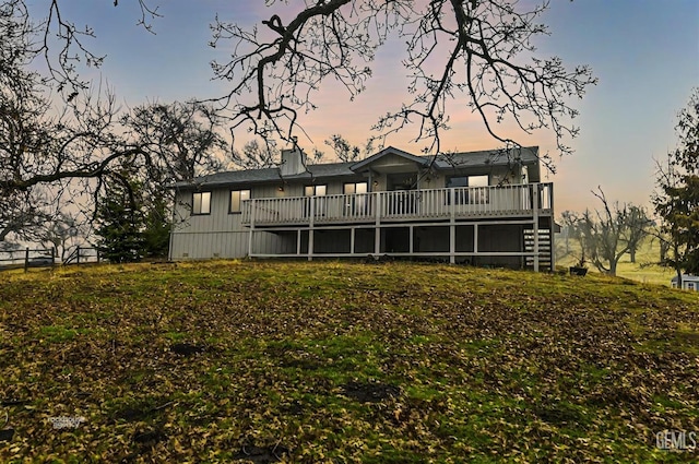 back house at dusk with a wooden deck