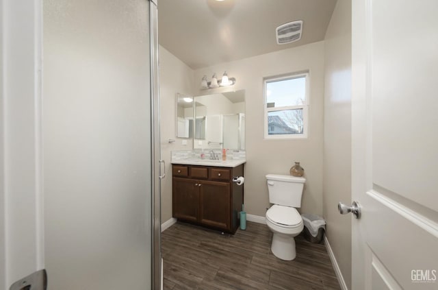 bathroom with baseboards, visible vents, toilet, wood finished floors, and vanity