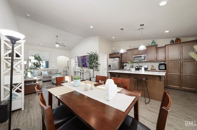 dining room with lofted ceiling, visible vents, arched walkways, and wood finished floors