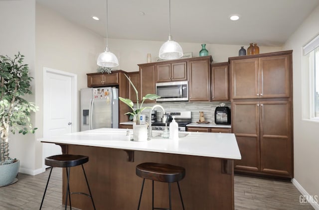 kitchen with lofted ceiling, tasteful backsplash, stainless steel appliances, and a kitchen breakfast bar