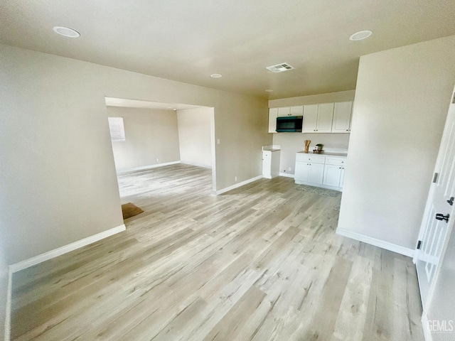 kitchen featuring white cabinetry, baseboards, visible vents, and light wood-type flooring