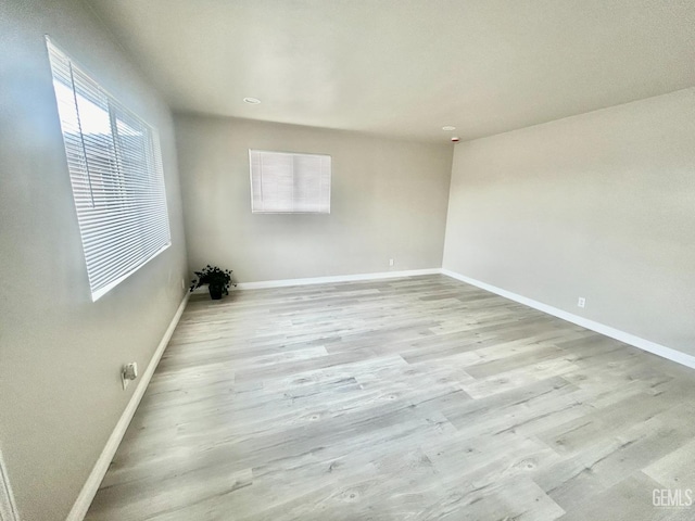 unfurnished room with baseboards and light wood-style flooring