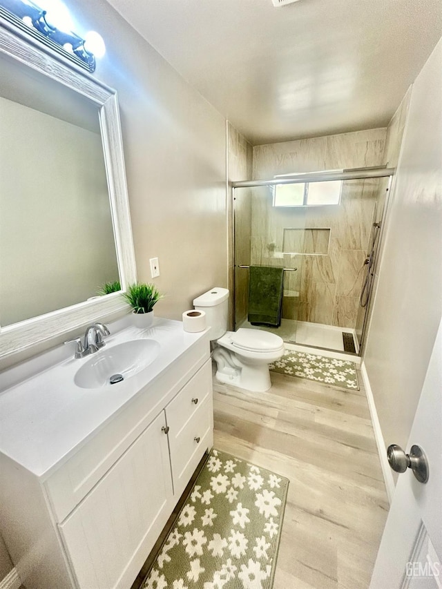 full bathroom featuring a shower stall, toilet, vanity, and wood finished floors