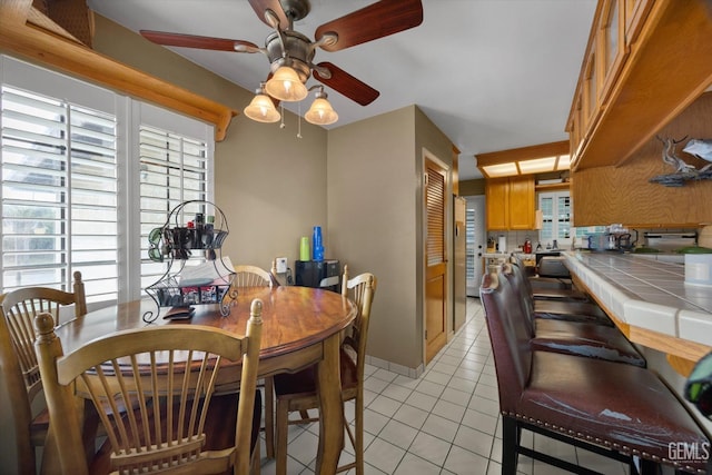 tiled dining space with ceiling fan