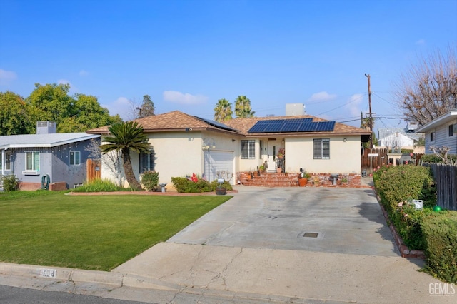 ranch-style home with a front yard, solar panels, and a garage