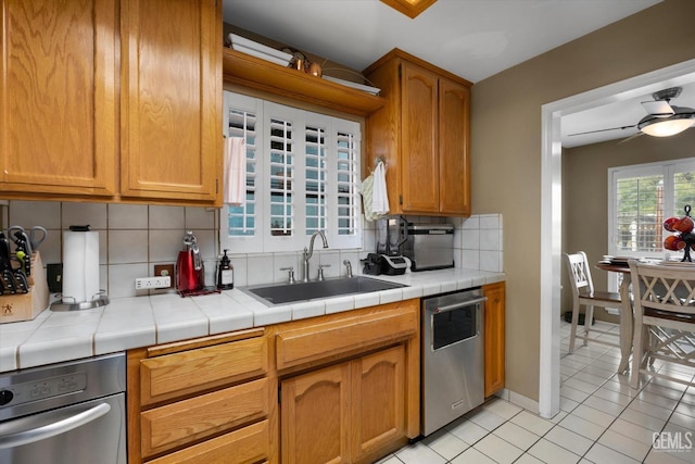 kitchen featuring tile counters, dishwasher, sink, and backsplash