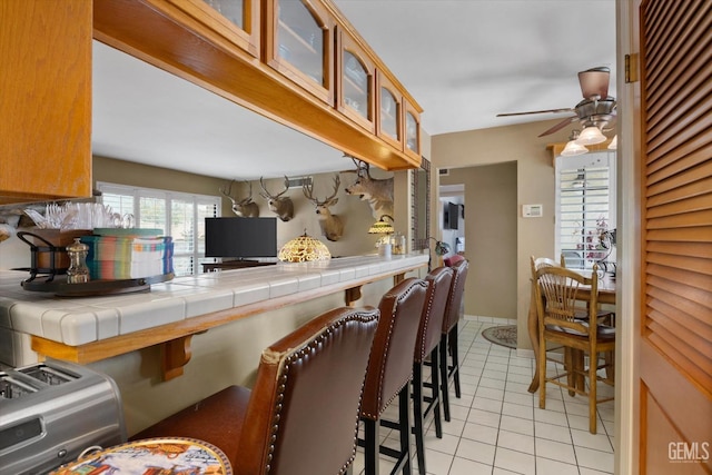 kitchen with ceiling fan, tile counters, and light tile patterned floors