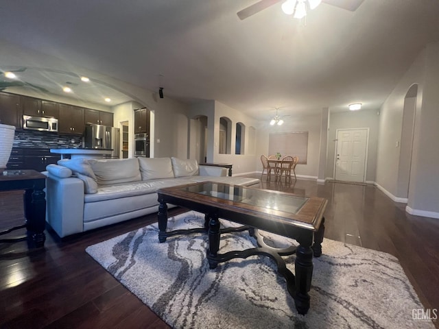 living room with ceiling fan and dark hardwood / wood-style flooring