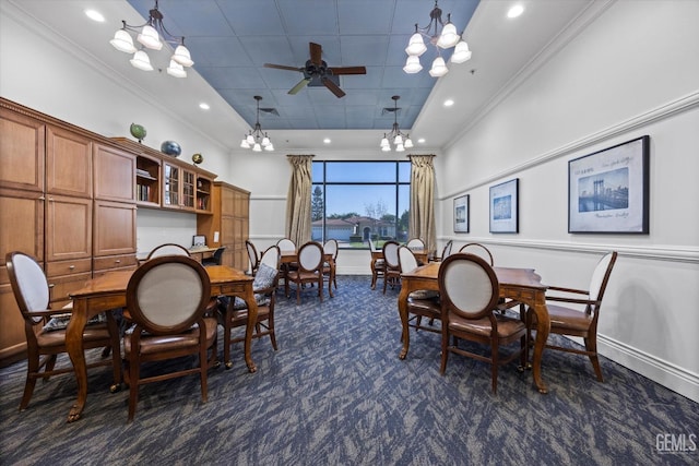 dining room with dark colored carpet, crown molding, ceiling fan with notable chandelier, and baseboards