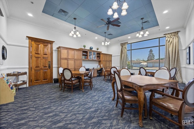 dining space with visible vents, ornamental molding, dark colored carpet, and a tray ceiling