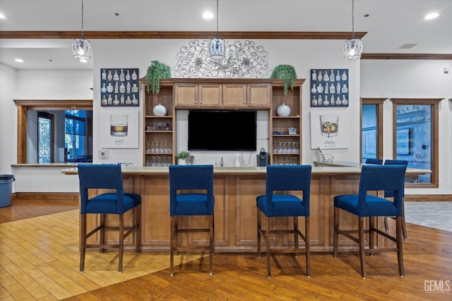 bar with decorative light fixtures, hardwood / wood-style floors, ornamental molding, and recessed lighting