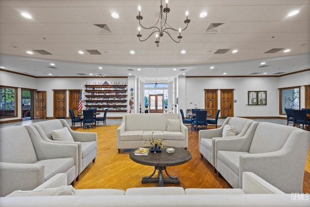 living room with ornamental molding, visible vents, wood finished floors, and a chandelier