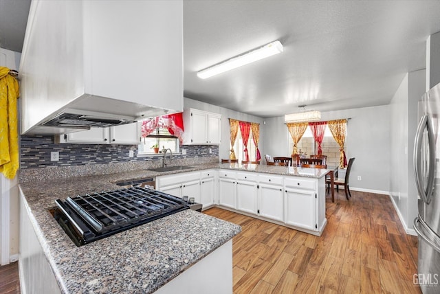 1914 Hummingbird Ave, Delano, CA 93215 - kitchen featuring a sink, exhaust hood, a peninsula, cooktop, and white cabinets