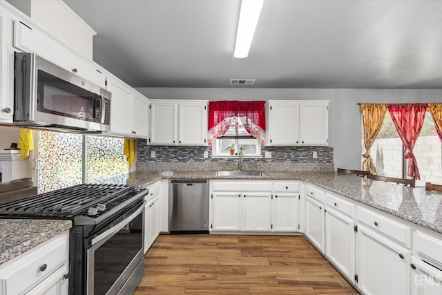 1914 Hummingbird Ave, Delano, CA 93215 - kitchen with appliances with stainless steel finishes, a sink, dark wood-style floors, white cabinetry, and healthy amount of natural light
