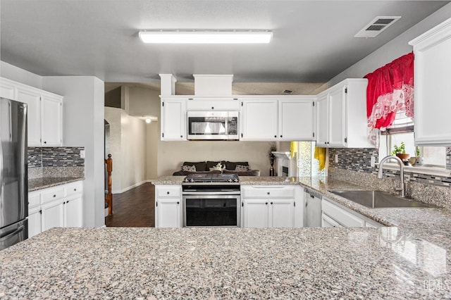 1914 Hummingbird Ave, Delano, CA 93215 - kitchen with stainless steel appliances, a sink, tasteful backsplash, white cabinetry, and a peninsula