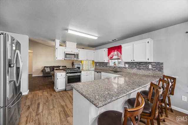 1914 Hummingbird Ave, Delano, CA 93215 - kitchen featuring appliances with stainless steel finishes, a peninsula, wood finished floors, backsplash, and baseboards