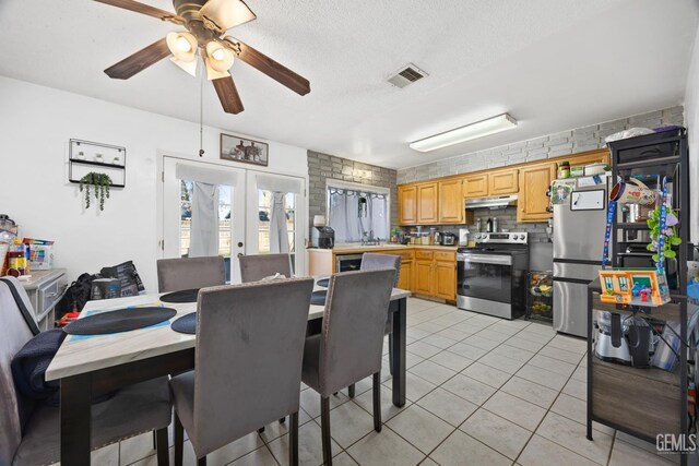 dining area with light tile patterned flooring, sink, ceiling fan, a textured ceiling, and french doors