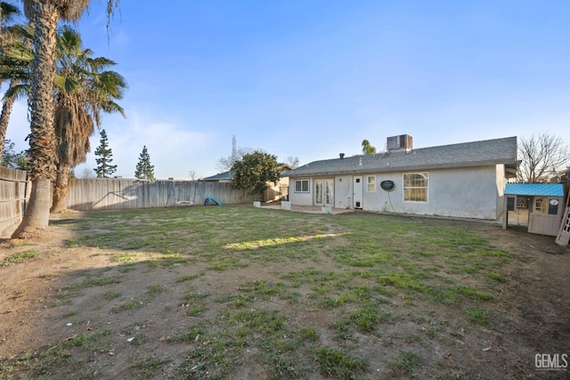 rear view of property featuring cooling unit and a yard