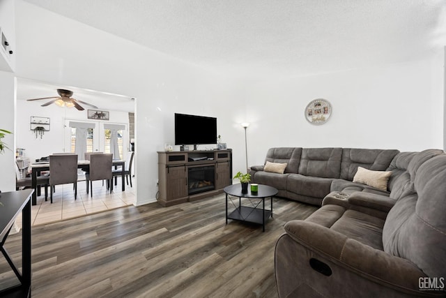 living room with hardwood / wood-style flooring, ceiling fan, and a textured ceiling