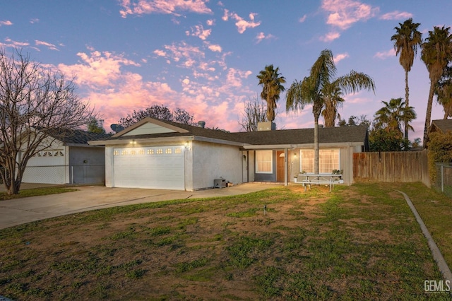 single story home featuring a garage and a lawn