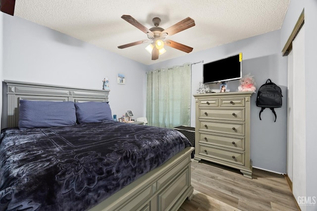 bedroom with ceiling fan, light hardwood / wood-style flooring, and a textured ceiling