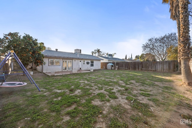 back of house with french doors, a patio, a playground, and a lawn