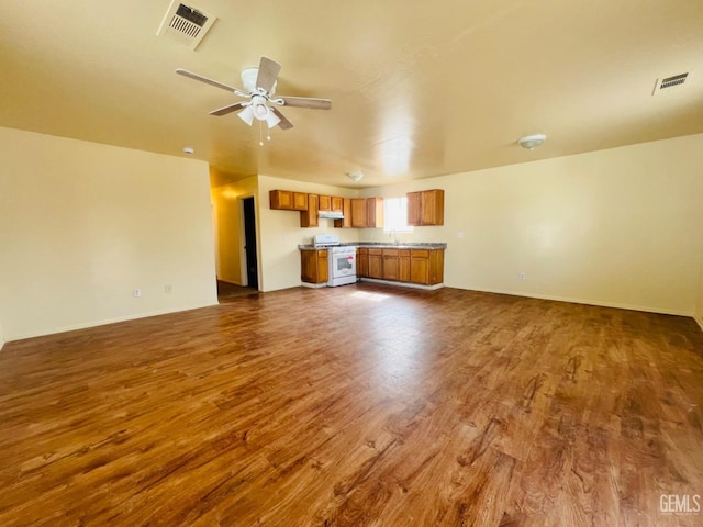 unfurnished living room featuring ceiling fan, sink, and dark hardwood / wood-style flooring