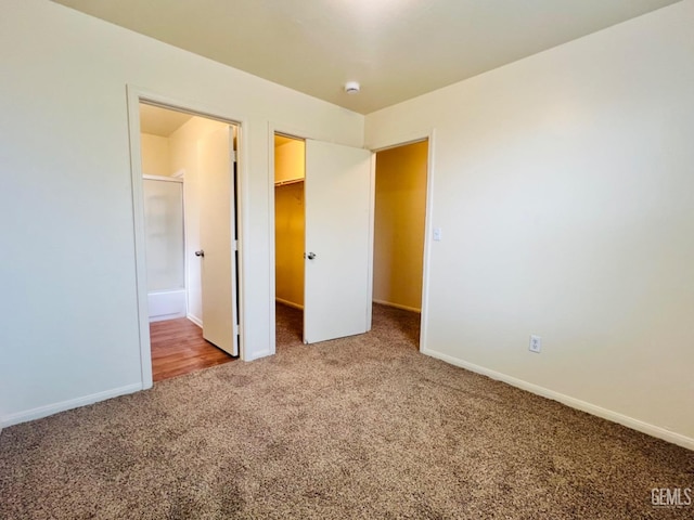 unfurnished bedroom with a closet, carpet flooring, connected bathroom, and a spacious closet