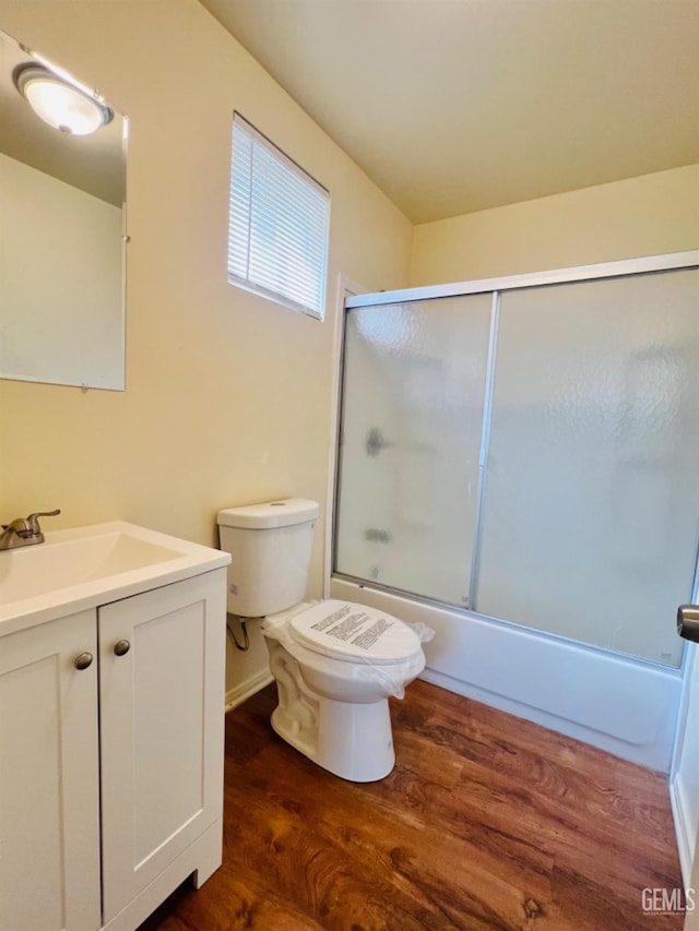 full bathroom with enclosed tub / shower combo, wood-type flooring, vanity, and toilet