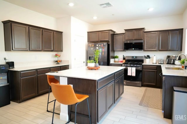 kitchen featuring dark brown cabinetry, sink, a breakfast bar area, a center island, and stainless steel appliances