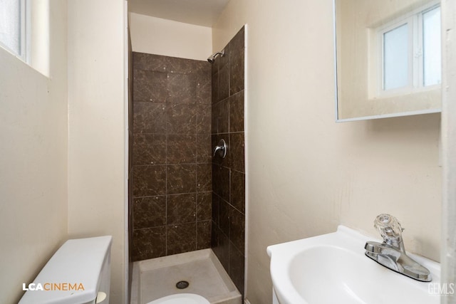 bathroom with tiled shower, toilet, and a healthy amount of sunlight