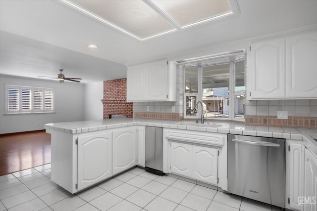 kitchen with dishwasher, white cabinetry, and tile counters